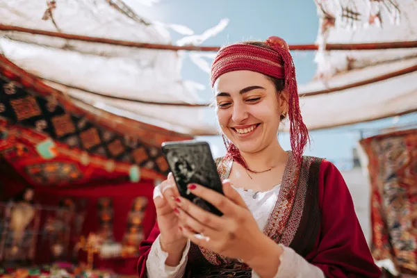 GEMJLL Mobile Casino — Play anytime, anywhere A player using their smartphone during a festive local event, representing GEMJLL’s fully mobile-friendly casino.